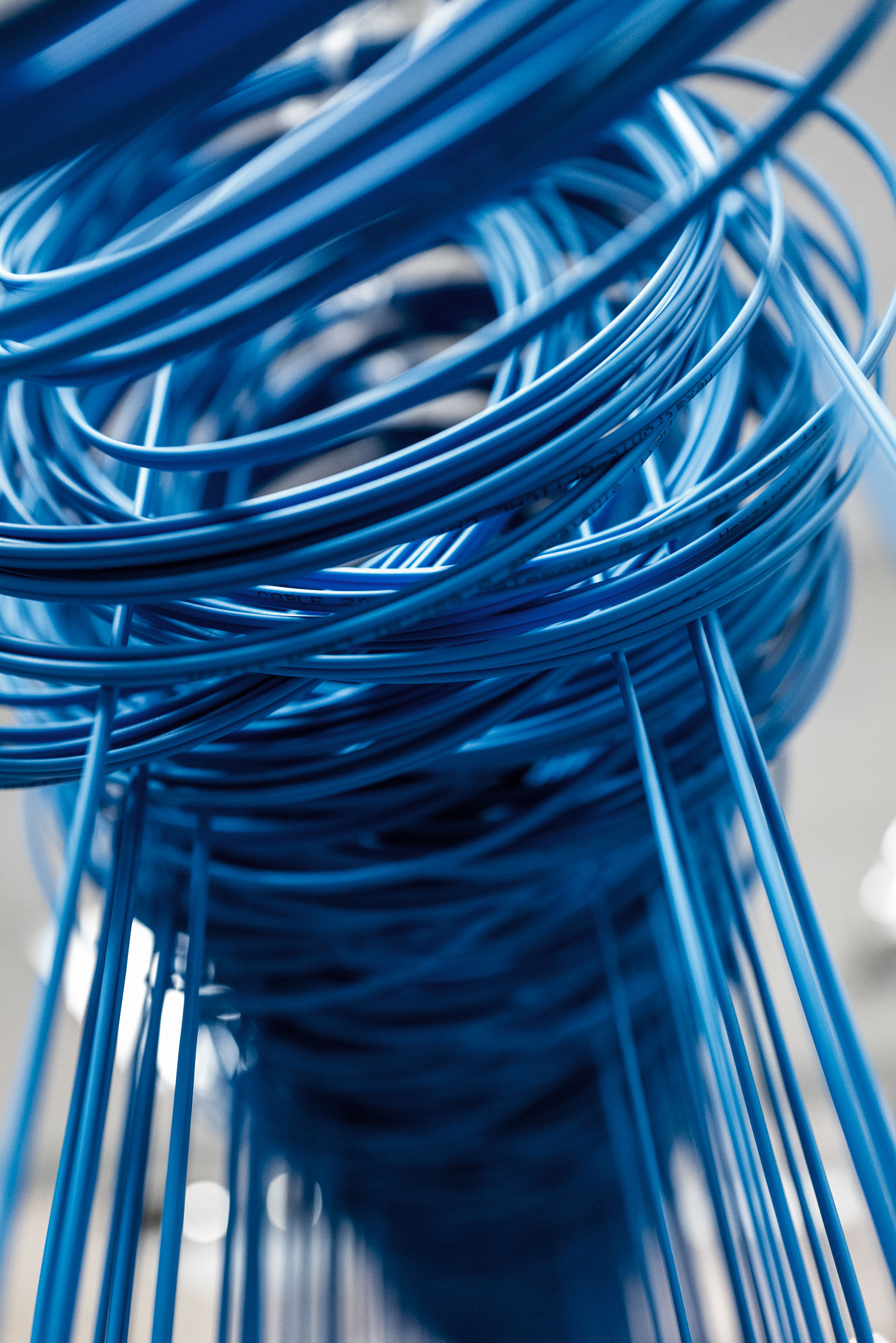 Close-up of fiber cables tangled in an intricate pattern, reflecting light, with a blurred background.